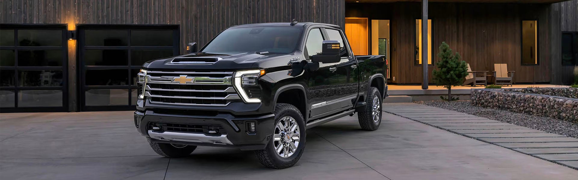 Black Chevrolet Silverado 1500 pickup truck parked outside a modern home.