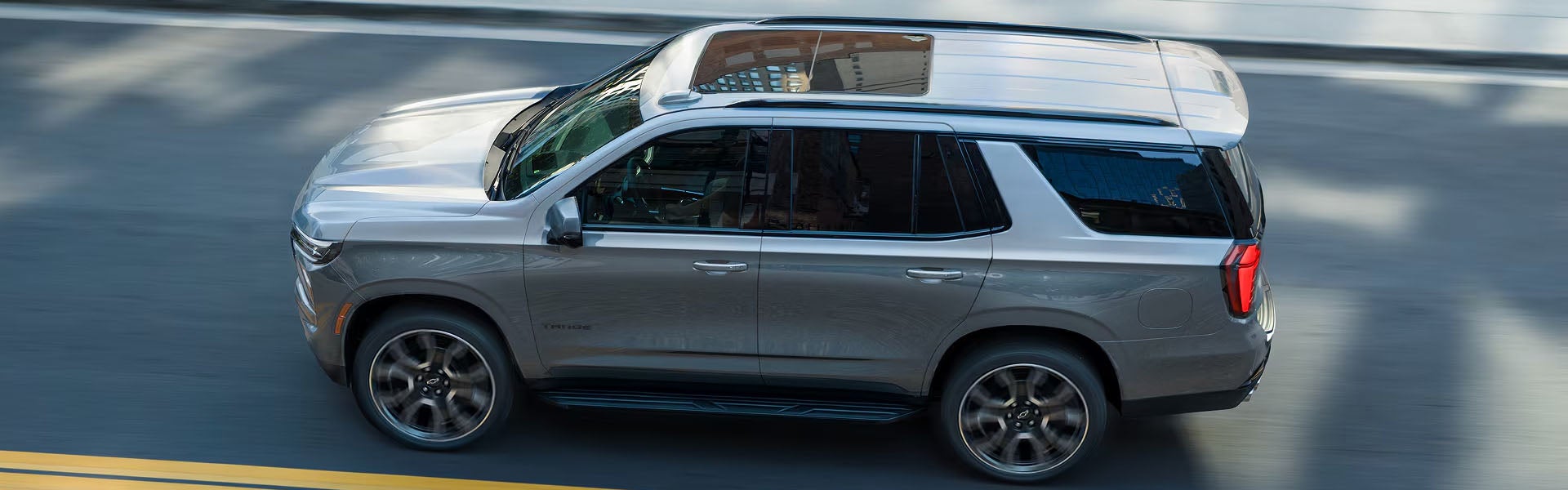 Silver Chevrolet Tahoe SUV driving on the road.