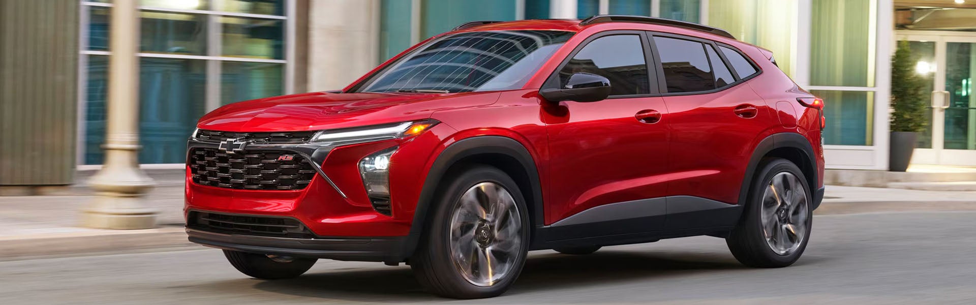 Red Chevrolet Trax driving through a city.